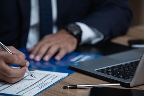 Closeup of person in a business suit signing a document.